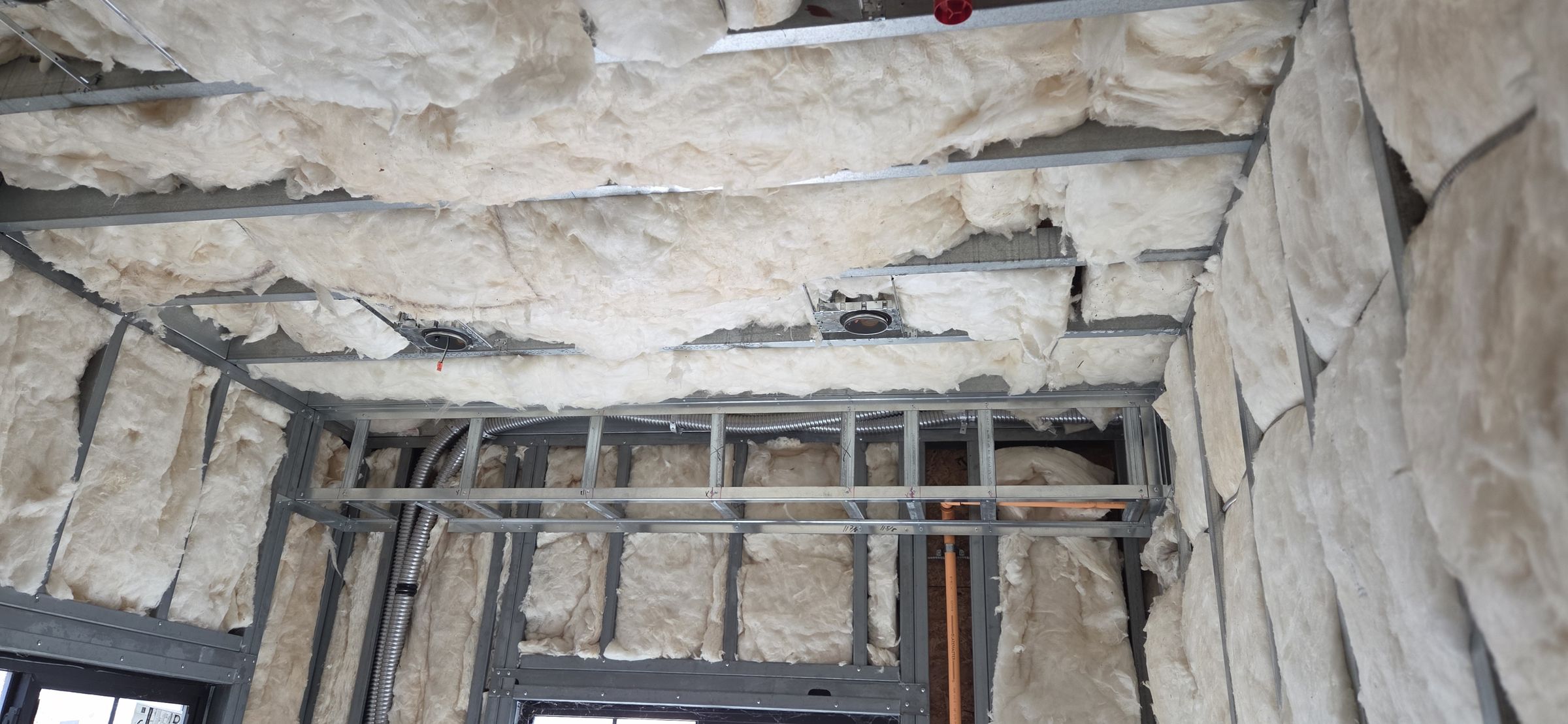 Ceiling framing and insulation coordinated overhead before boarding